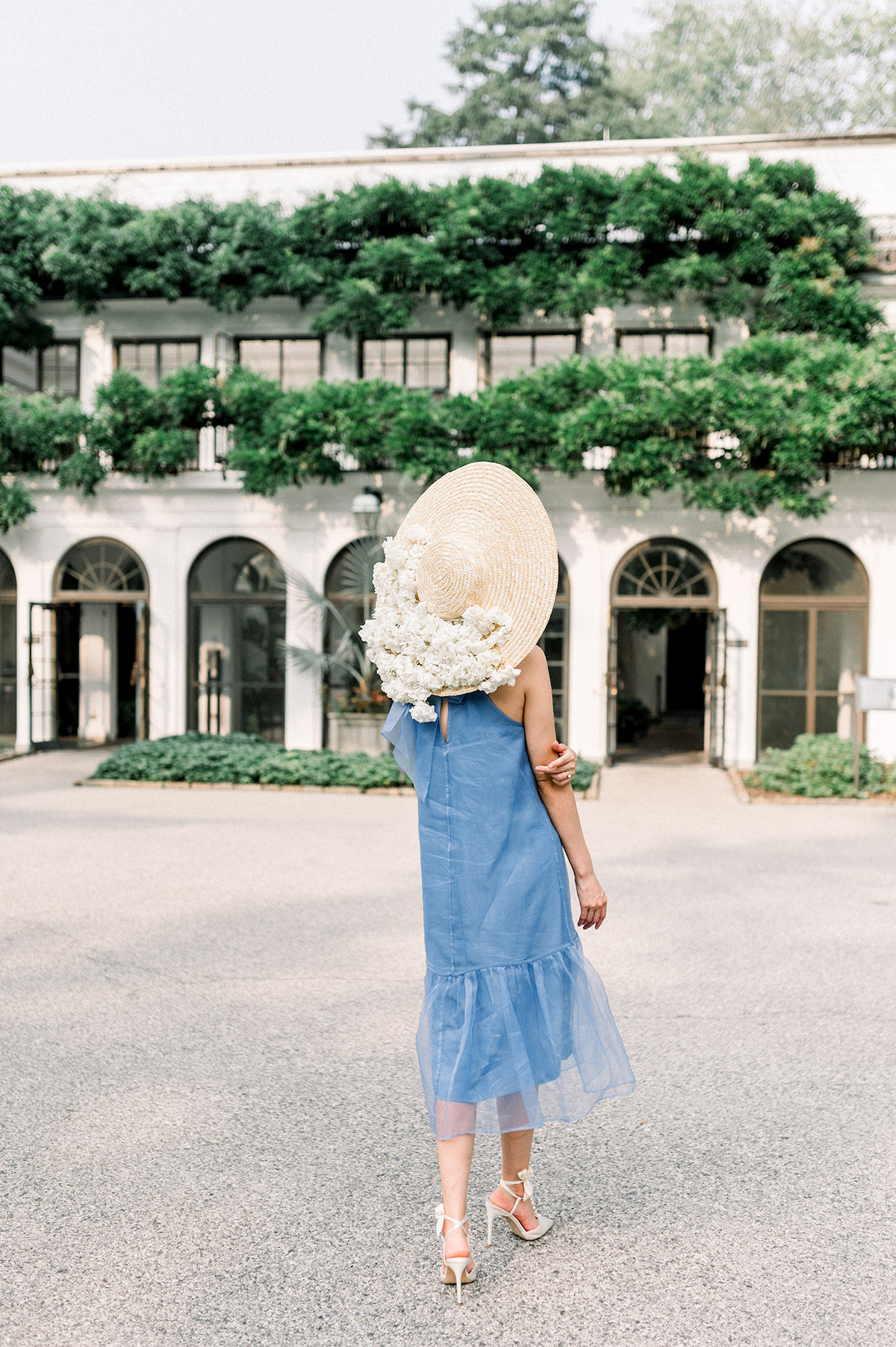 Karla's presence is a vision of sophistication against the backdrop of a historic house at Longwood Gardens, her Anthropologie French blue gown and elegant hat creating a harmonious blend of past and present.