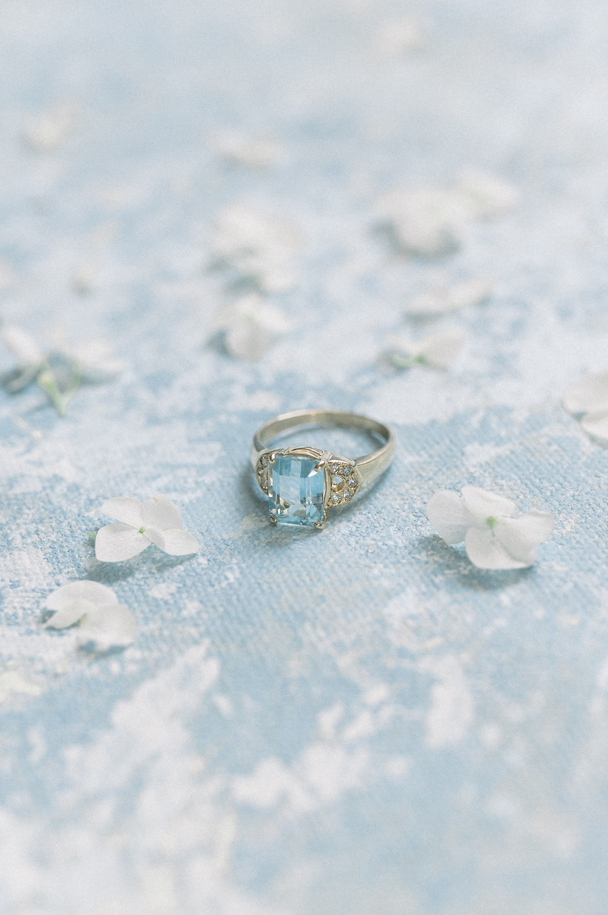 Elegant flat lay composition featuring the vintage engagement ring, a cherished and elegant accessory that adds a touch of history to the bridal ensemble set against a hand-painted backdrop.