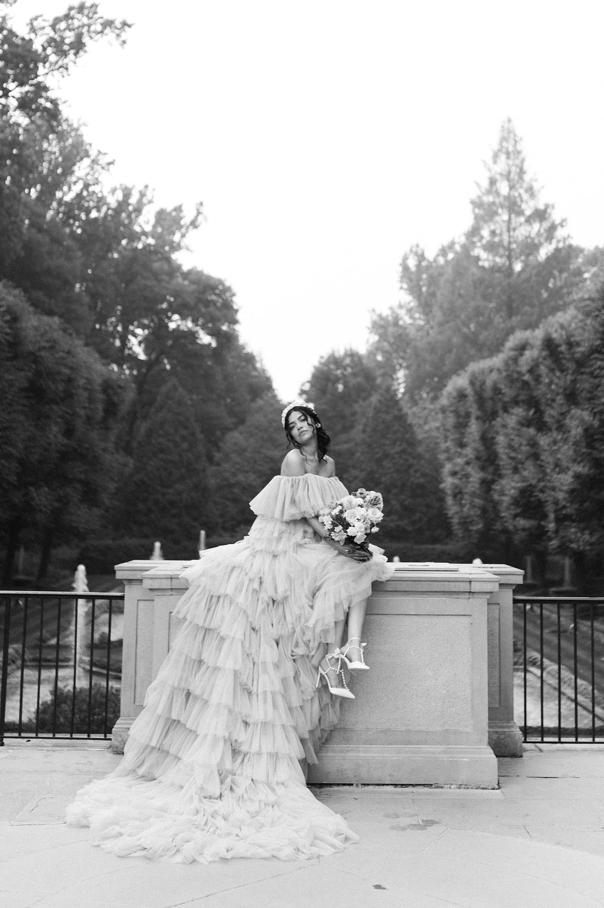 In this timeless black and white image, Karla's allure shines through as she wears the tiered couture gown, adding a touch of classic charm to the garden surroundings.