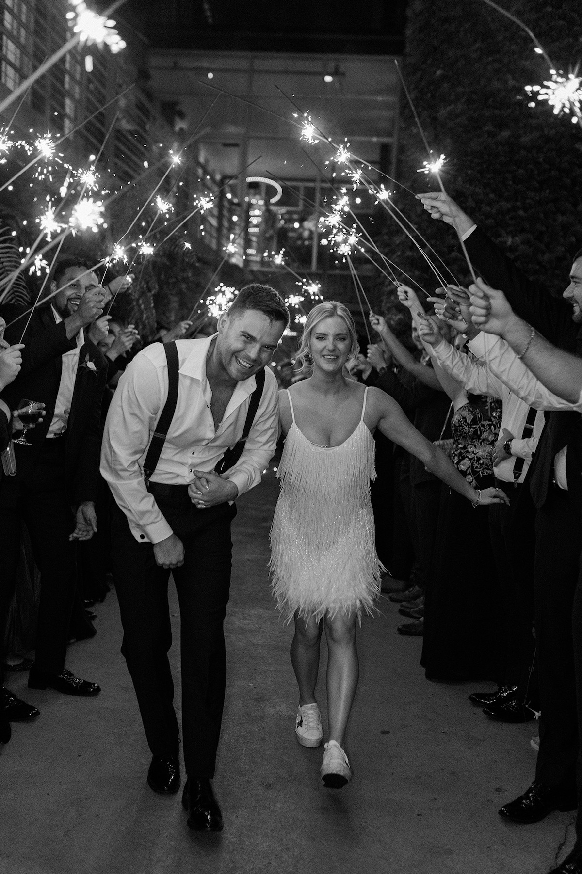 A sparkler send-off illuminates the night as guests bid farewell to the newlyweds, marking the end of a joyous celebration at Kelly and Adam's wedding.
