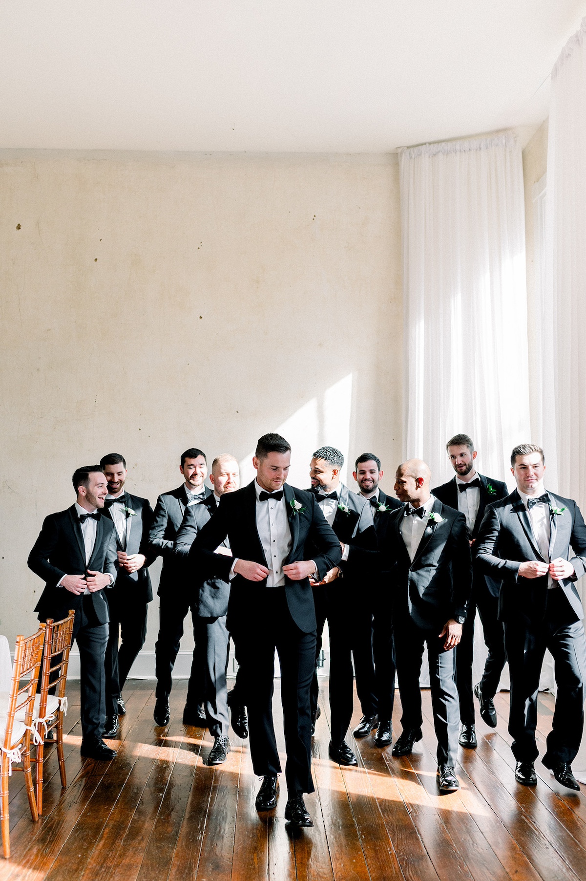 Candid editorial shot capturing the camaraderie of groomsmen, exuding timeless sophistication in every gesture.