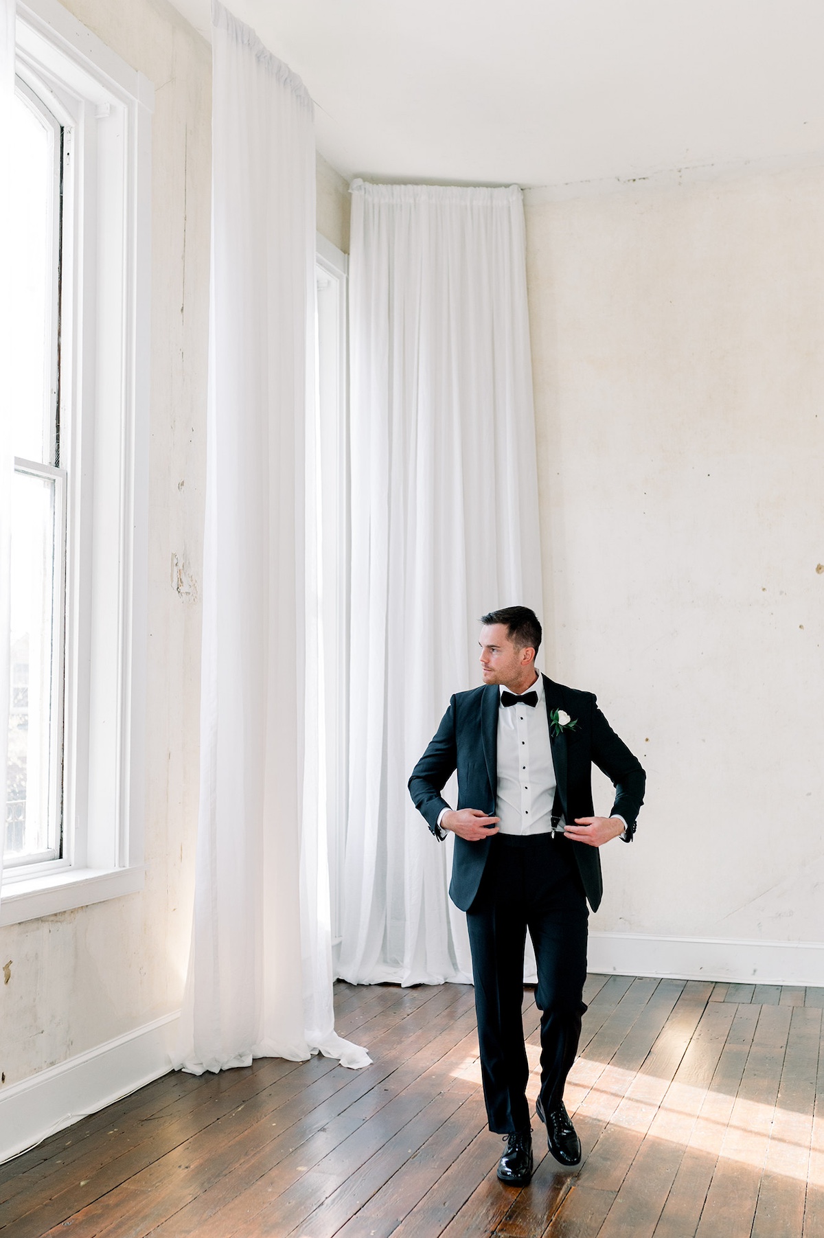 Artful editorial portrait of the groom, basking in natural light, emphasizing the high-end details of his wedding attire.