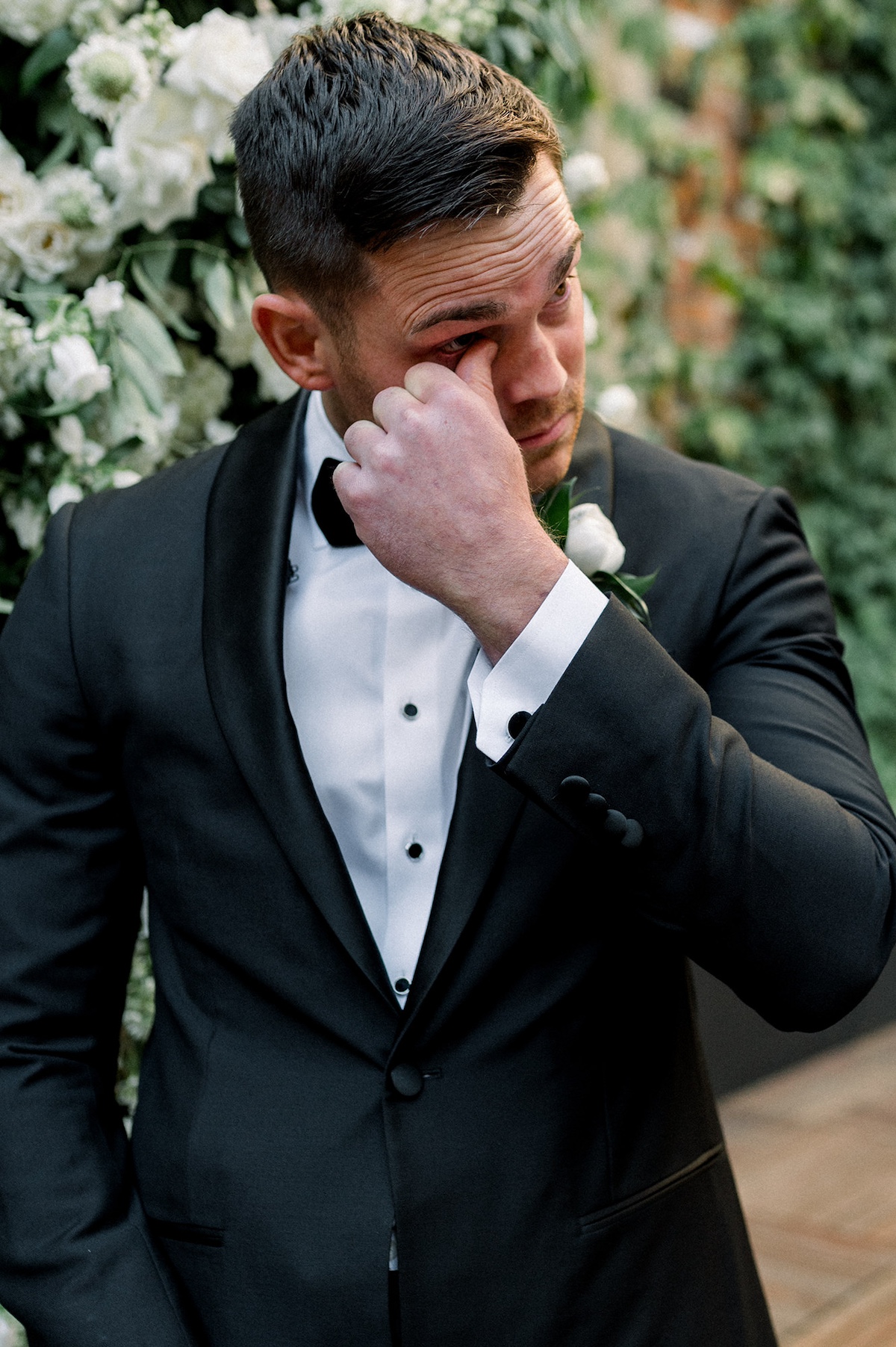 Candid editorial moment capturing the groom's heartfelt reaction to the bride's entrance, a high-end display of genuine emotion.