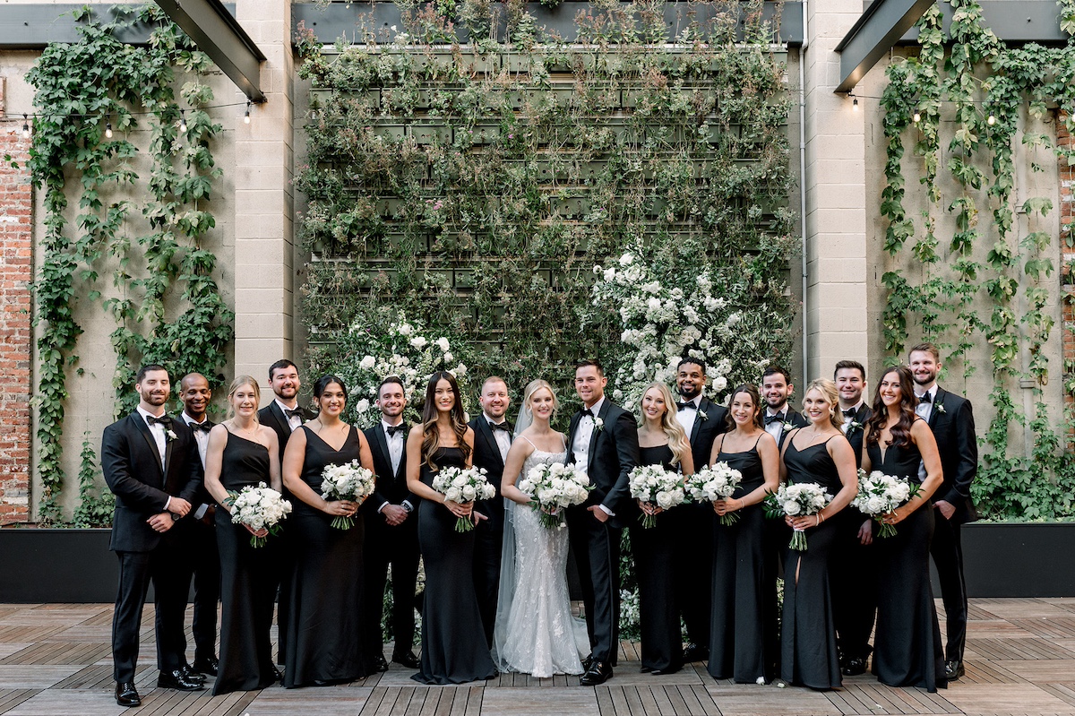 A timeless editorial group pose featuring the full wedding party, exuding high-end style and a collective sense of sophistication.