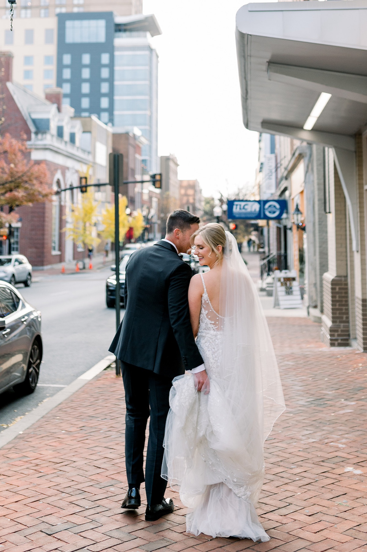 Cobblestone charm editorial portrait in Lancaster City, the bride and groom walking hand in hand, capturing the high-end romance of city life.