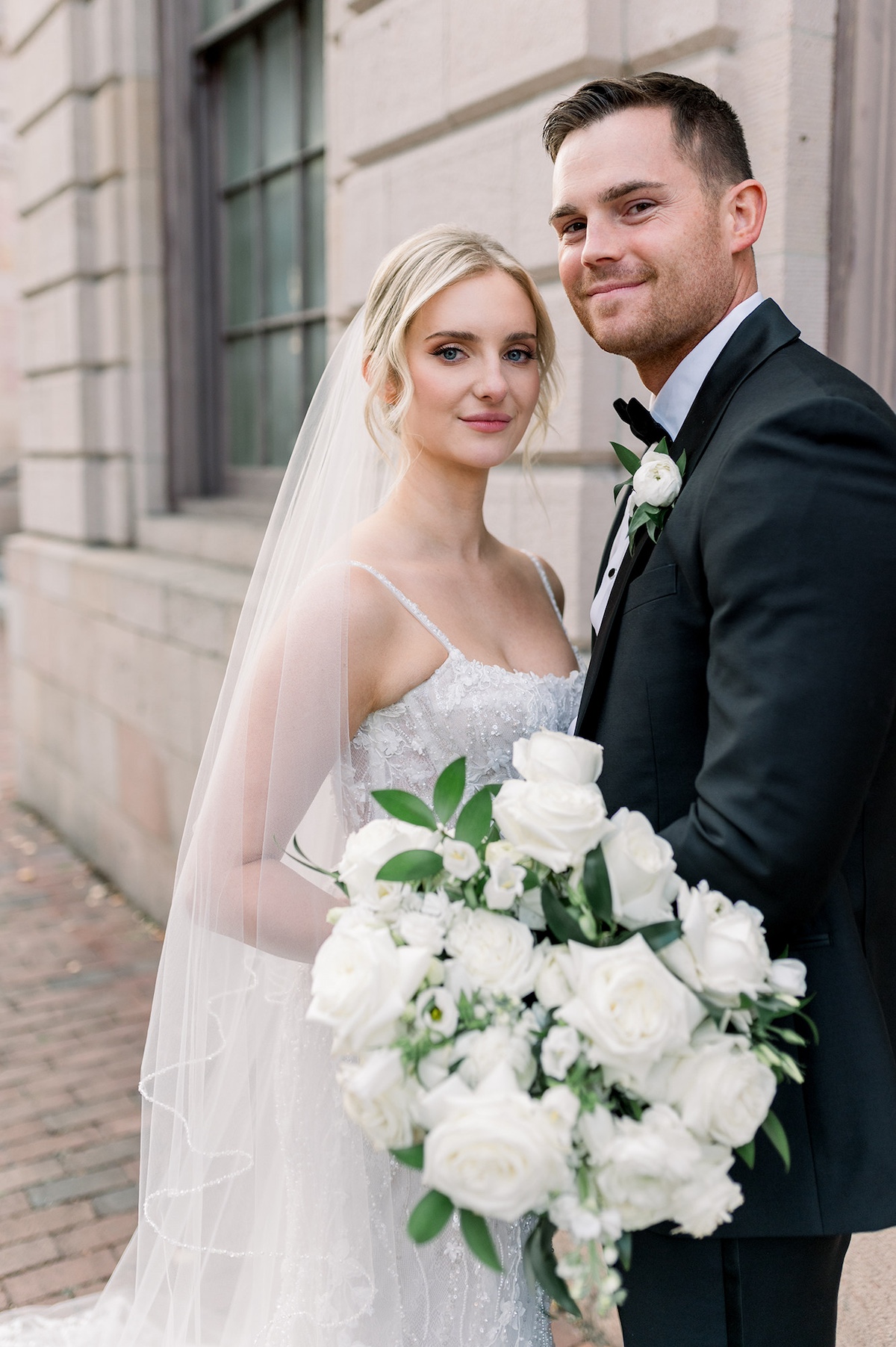 Embracing against classic architecture, the bride and groom showcase their high-end connection in a portrait capturing timeless romance in Lancaster City.