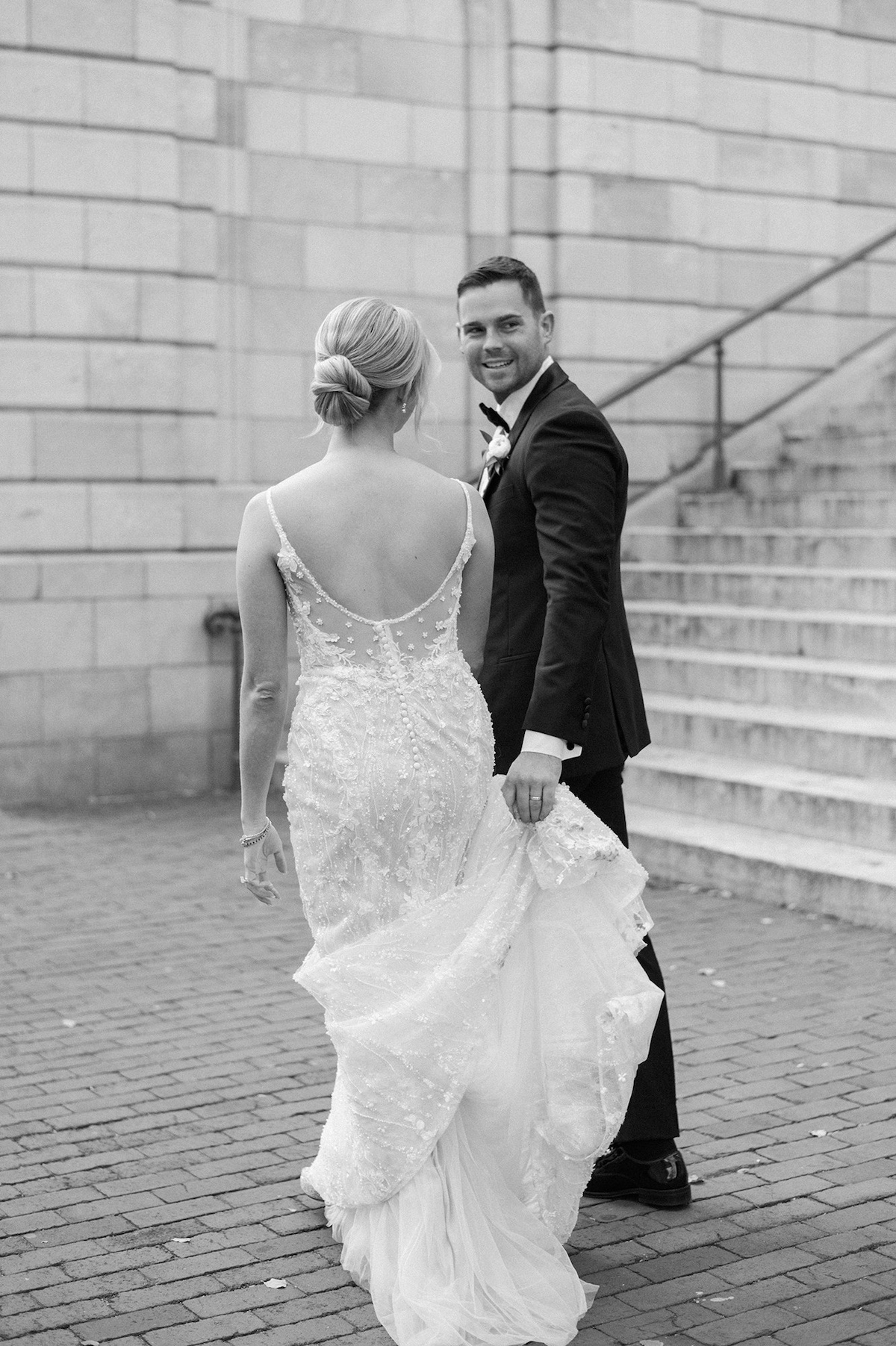 Chic editorial portrait capturing a leisurely stroll through urban alleys of Lancaster City, the bride and groom immersed in high-end urban charm.
